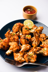 Tandoori Gobi / Roasted cauliflower Tikka is a dry dish made by roasting Cauliflowers in Oven/Tandoor. It's  popular starter food from India. served with ketchup. selective focus