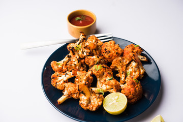 Tandoori Gobi / Roasted cauliflower Tikka is a dry dish made by roasting Cauliflowers in Oven/Tandoor. It's  popular starter food from India. served with ketchup. selective focus