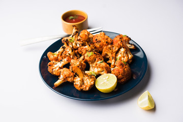 Tandoori Gobi / Roasted cauliflower Tikka is a dry dish made by roasting Cauliflowers in Oven/Tandoor. It's  popular starter food from India. served with ketchup. selective focus