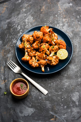 Tandoori Gobi / Roasted cauliflower Tikka is a dry dish made by roasting Cauliflowers in Oven/Tandoor. It's  popular starter food from India. served with ketchup. selective focus