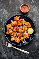 Tandoori Gobi / Roasted cauliflower Tikka is a dry dish made by roasting Cauliflowers in Oven/Tandoor. It's  popular starter food from India. served with ketchup. selective focus