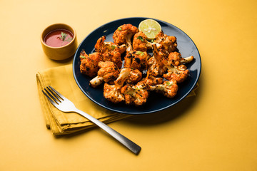 Tandoori Gobi / Roasted cauliflower Tikka is a dry dish made by roasting Cauliflowers in Oven/Tandoor. It's  popular starter food from India. served with ketchup. selective focus