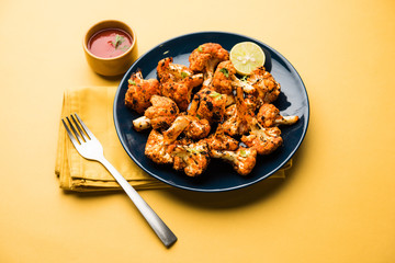 Tandoori Gobi / Roasted cauliflower Tikka is a dry dish made by roasting Cauliflowers in Oven/Tandoor. It's  popular starter food from India. served with ketchup. selective focus