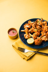 Tandoori Gobi / Roasted cauliflower Tikka is a dry dish made by roasting Cauliflowers in Oven/Tandoor. It's  popular starter food from India. served with ketchup. selective focus