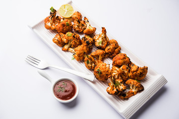 Tandoori Gobi / Roasted cauliflower Tikka is a dry dish made by roasting Cauliflowers in Oven/Tandoor. It's  popular starter food from India. served with ketchup. selective focus