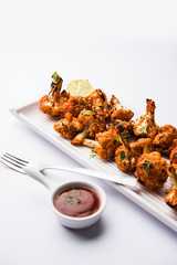 Tandoori Gobi / Roasted cauliflower Tikka is a dry dish made by roasting Cauliflowers in Oven/Tandoor. It's  popular starter food from India. served with ketchup. selective focus