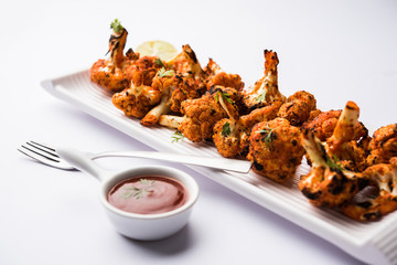 Tandoori Gobi / Roasted cauliflower Tikka is a dry dish made by roasting Cauliflowers in Oven/Tandoor. It's  popular starter food from India. served with ketchup. selective focus