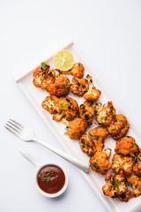Tandoori Gobi / Roasted cauliflower Tikka is a dry dish made by roasting Cauliflowers in Oven/Tandoor. It's  popular starter food from India. served with ketchup. selective focus