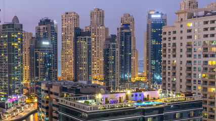Aerial view of Dubai Marina after sunset from a vantage point day to night timelapse.
