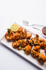 Tandoori Gobi / Roasted cauliflower Tikka is a dry dish made by roasting Cauliflowers in Oven/Tandoor. It's  popular starter food from India. served with ketchup. selective focus