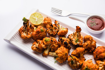 Tandoori Gobi / Roasted cauliflower Tikka is a dry dish made by roasting Cauliflowers in Oven/Tandoor. It's  popular starter food from India. served with ketchup. selective focus