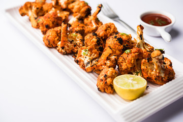 Tandoori Gobi / Roasted cauliflower Tikka is a dry dish made by roasting Cauliflowers in Oven/Tandoor. It's  popular starter food from India. served with ketchup. selective focus