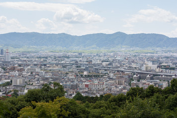 Kyoto city in Kyoto, Japan. The view from Kiyomizu-dera temple make it looks like a hidden city in a mysterious place that surrounded by mountains and trees.  