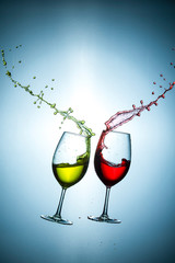 Two Types of Colorful Red and Light Yellow Wine Splashes Poured Out from Glasses Against Bluish Background. Short Flash Duration for Freezing Motion Used. Vertical Shot