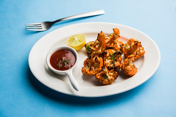 Tandoori Gobi / Roasted cauliflower Tikka is a dry dish made by roasting Cauliflowers in Oven/Tandoor. It's  popular starter food from India. served with ketchup. selective focus