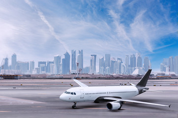 Fototapeta na wymiar Airplane at Doha airport, cityscape view with skyscrapers in background.  Plane with building,  planes and cities.
