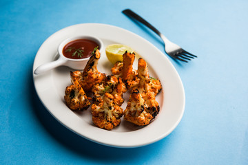Tandoori Gobi / Roasted cauliflower Tikka is a dry dish made by roasting Cauliflowers in Oven/Tandoor. It's  popular starter food from India. served with ketchup. selective focus