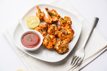 Tandoori Gobi / Roasted cauliflower Tikka is a dry dish made by roasting Cauliflowers in Oven/Tandoor. It's  popular starter food from India. served with ketchup. selective focus