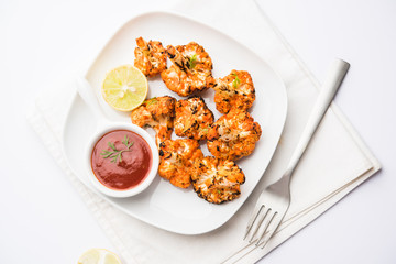 Tandoori Gobi / Roasted cauliflower Tikka is a dry dish made by roasting Cauliflowers in Oven/Tandoor. It's  popular starter food from India. served with ketchup. selective focus