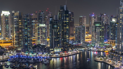 Fototapeta na wymiar Luxury Dubai Marina canal with passing boats and promenade night timelapse, Dubai, United Arab Emirates
