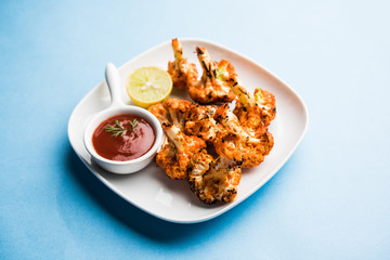 Tandoori Gobi / Roasted cauliflower Tikka is a dry dish made by roasting Cauliflowers in Oven/Tandoor. It's  popular starter food from India. served with ketchup. selective focus
