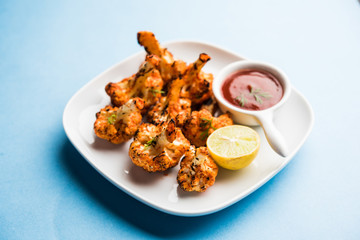 Tandoori Gobi / Roasted cauliflower Tikka is a dry dish made by roasting Cauliflowers in Oven/Tandoor. It's  popular starter food from India. served with ketchup. selective focus