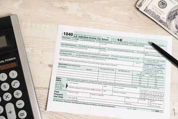 US tax form 1040 with pen, calculator and dollar bills. tax form law document usa white business concept