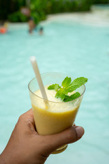 a hand holding a glass of fresh banana milk juice
