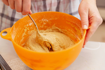 Kneading dough in a plastic bowl in the kitchen, close-up