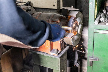 Worker with a grinder machine in a factory