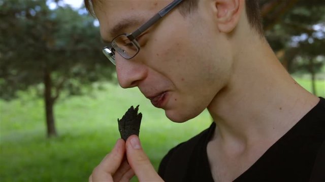 The Guy Takes A Bite Of His Black Ice Cream Cone. Female Hand Appears In The Frame And Robs The Guy Of The Last Piece. Real Time, Outdoor, Park, Heat, Profile, Contains People