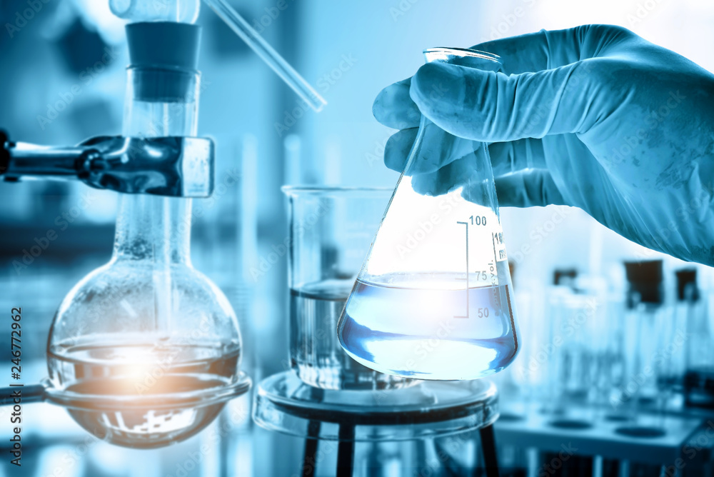 Wall mural hand of scientist holding flask with lab glassware in chemical laboratory background, science labora