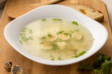 clear meat (chicken) broth with cut quail eggs, spices and greenery