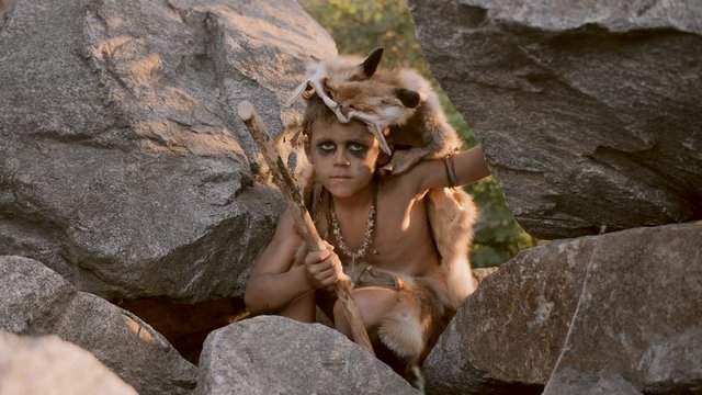 Caveman, manly boy hunting outdoors. Ancient warrior portrait.