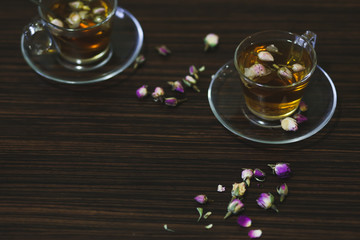 Rose oriental tea in transparent glass cups on dark wood background.