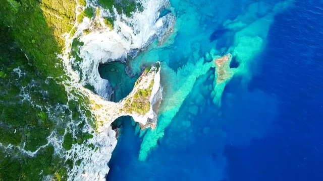 Aerial bird's eye view video taken by drone of caves  and boats docked in caribbean tropical beach with turquoise - sapphire waters and caves forming a blue lagoon