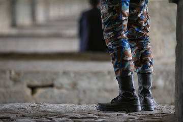 Iranian army soldier foot with uniform under Arches of a beautiful historic Khan bridge over Zayandeh River in Isfahan, Iran (also known as Khaju, Si-o-seh pol)