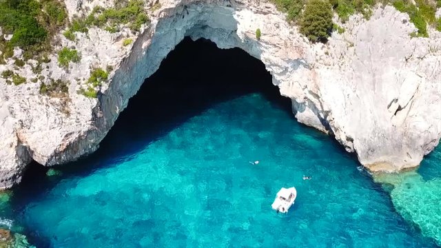 Aerial bird's eye view video taken by drone of caves  and boats docked in caribbean tropical beach with turquoise - sapphire waters and caves forming a blue lagoon