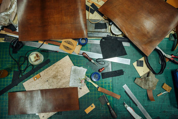 Leatherworking tools. Riveter, awl, ruler, pliers, tassels, pencil, leather pieces, rivets and fasteners are on the table. Close up photo.