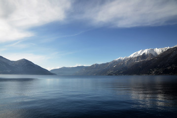 Fototapeta na wymiar Alpine Lake Maggiore with Snow-capped Mountain and Blue Sky with Clouds in Switzerland.