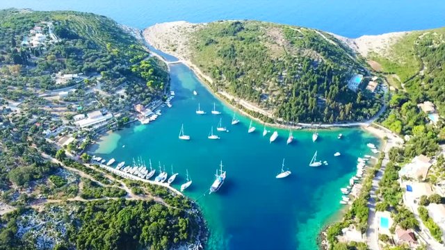 Aerial drone bird's eye view video of tropical rocky small safe bay of Mogonisi with sail boats docked, Paxos island, Ionian, Greece