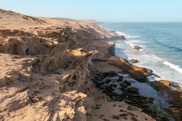 Fototapeta na wymiar Atlantic coast waves are crashing into rocky cliffs near Agadir, Morocco