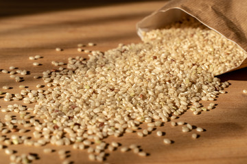 Raw Brown Rice On A wooden table. Organic Brown Rice On A table With Bag In The Background.