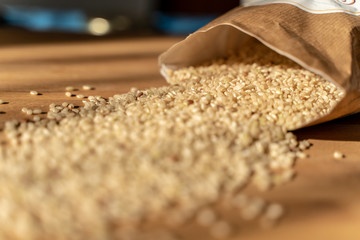 Raw Brown Rice On A wooden table With Bag In The Background. Organic Brown Rice On A table.