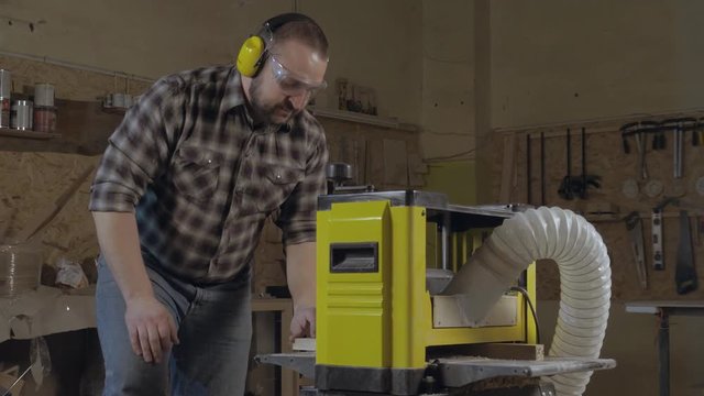 Carpenter cutting a wood into pieces. Works with electric saw machine.