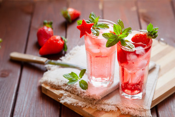 Sparkling pink strawberry lemonade on dark wooden background