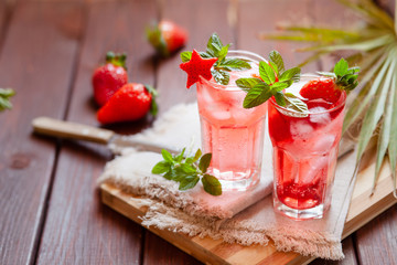Sparkling pink strawberry lemonade on dark wooden background