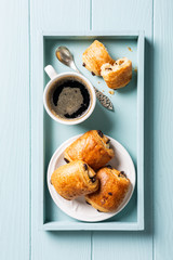 Breakfast with mini fresh croissants bun with chocolate and coffee cup on blue turquoise background. Top view.