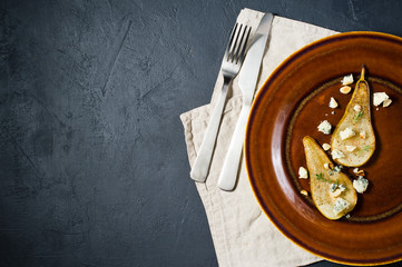 baked pear with Gorgonzola, nuts and mango sauce, top view, black background, space for text