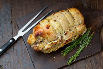 Baked pork shoulder with pepper, rosemary and garlic, vintage wooden background, selective focus